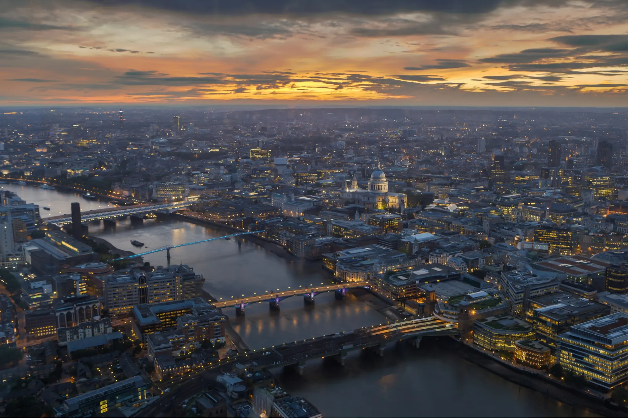 Central London from the air at dusk, the Thames lit below